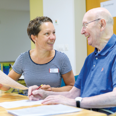 Senior im Gespräch mit einer Aktivierungstherapeutin