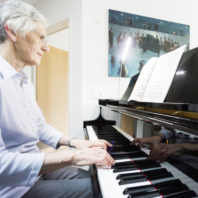 Seniorin am Flügel in ihrer Wohnung